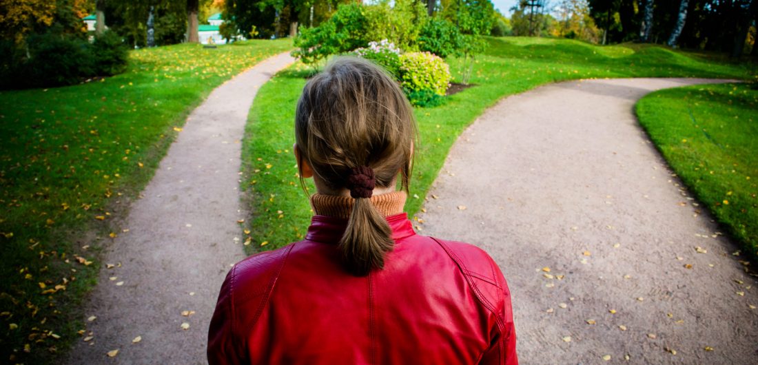 Girl in red jacket standing on the fork of two roads.