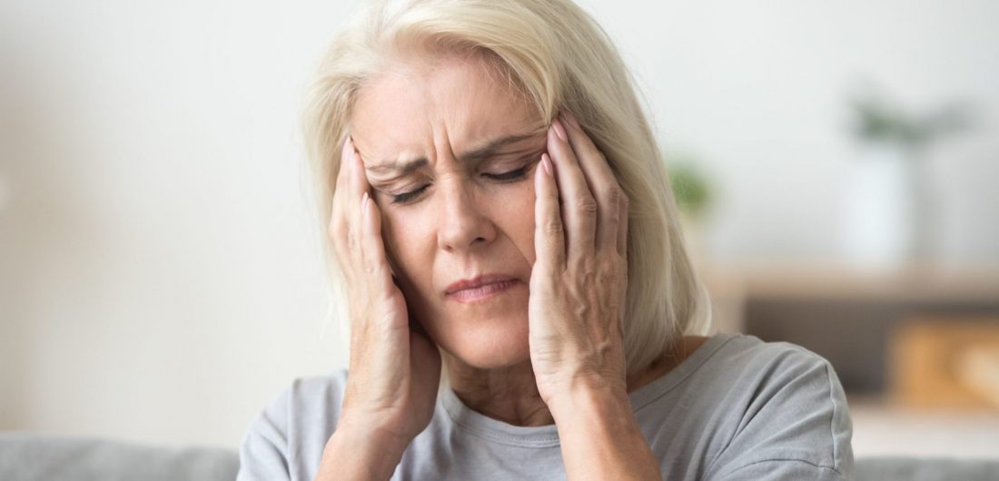 Upset older woman touching temples aching head feeling strong headache